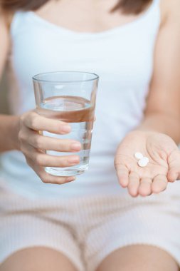Kadının elinde ağrı kesici hap ve su bardağı vardı. Baş ağrısı, mide ağrısı, gıda zehirlenmesi, endometriyozis, histerektomi ve regl ağrıları için.