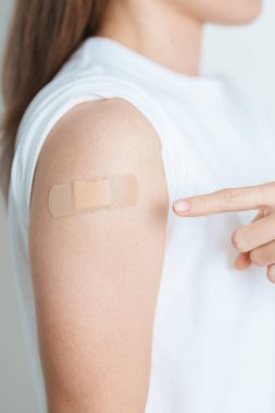 Woman with bandage after receiving vaccine. Vaccination and Immunization for Influenza, HPV, Zoster, IPD, DTP or Diphtheria, Tetanus and Pertussis, MMR, Hepatitis B, Covid  and Varicella vaccine clipart