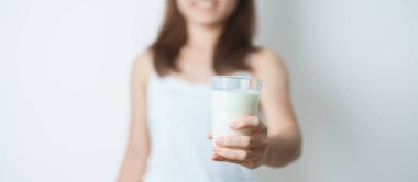 Süt içeceği ve günlük rutin konsepti. Genç bir kadın evde yüksek kalsiyum ve beslenme ile süt içiyor, kadın bardakta protein ile soya sütü tutuyor. Sağlıklı, sağlıklı ve mutlu bir yaşam tarzı.