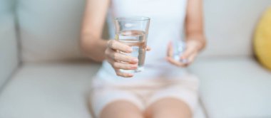 Kadının elinde ağrı kesici hap ve su bardağı vardı. Baş ağrısı, mide ağrısı, gıda zehirlenmesi, endometriyozis, histerektomi ve regl ağrıları için.