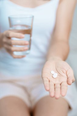 Kadının elinde ağrı kesici hap ve su bardağı vardı. Baş ağrısı, mide ağrısı, gıda zehirlenmesi, endometriyozis, histerektomi ve regl ağrıları için.