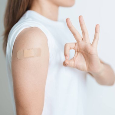 Aşı olduktan sonra bandajlı bir kadın. Grip aşısı, HPV, Zoster, IPD, DTP veya Difteri, Tetanos ve Pertusis, MMR, Hepatit B, Covid ve Varicella aşısı