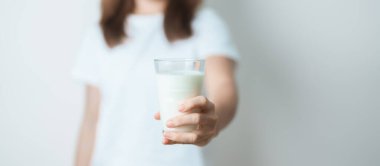 Süt içeceği ve günlük rutin konsepti. Genç bir kadın evde yüksek kalsiyum ve beslenme ile süt içiyor, kadın bardakta protein ile soya sütü tutuyor. Sağlıklı, sağlıklı ve mutlu bir yaşam tarzı.