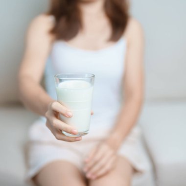 Süt içeceği ve günlük rutin konsepti. Genç bir kadın evde yüksek kalsiyum ve beslenme ile süt içiyor, kadın bardakta protein ile soya sütü tutuyor. Sağlıklı, sağlıklı ve mutlu bir yaşam tarzı.