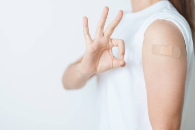 Aşı olduktan sonra bandajlı bir kadın. Grip aşısı, HPV, Zoster, IPD, DTP veya Difteri, Tetanos ve Pertusis, MMR, Hepatit B, Covid ve Varicella aşısı