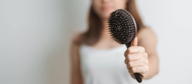 Saç bakımı ve günlük rutin kavramlar. Sabahları elinde tarak ve saç fırçası tutan Asyalı bir kadın. Genç bir kadın evde uzun düz saçlı bir saç fırçası tutuyor.