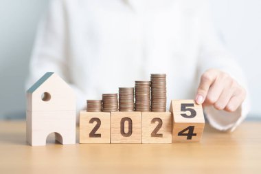 2024 yılı bitiminde ev modeli ve madeni paralarla mutlu yıllar 2025 'e. gayrimenkul, konut kredisi, vergi, yatırım, mortgage, finans, tasarruf ve yeni yıl kararı kavramları