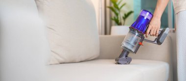 Kablosuz elektrik süpürgesiyle kanepeyi temizleyen kadın. Ev hanımı kablosuz süpürgeyi evi temizlemek için kullanıyor. Ev işleri, Temizlik, Temizlik, Temizlik, Toz, Temizlik ve günlük rutin