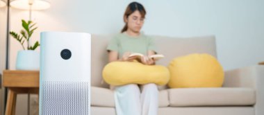 Air Purifier with woman read and relax on sofa. Purification system for filter and cleaning dust PM2.5 HEPA and virus in home. Allergy, Pure air, health lifestyle, Wellness life and Air Pollution clipart