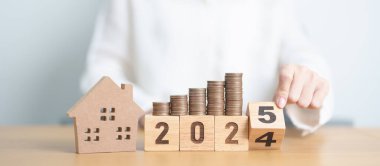 2024 yılı bitiminde ev modeli ve madeni paralarla mutlu yıllar 2025 'e. gayrimenkul, konut kredisi, vergi, yatırım, mortgage, finans, tasarruf ve yeni yıl kararı kavramları