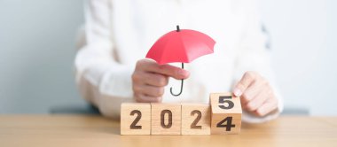 2024 yılı bitiminde kırmızı şemsiyeli mutlu yıllar 2025. Sigorta, koruma, güvenlik ve yeni yıl tatili kavramları