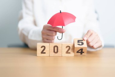 2024 yılı bitiminde kırmızı şemsiyeli mutlu yıllar 2025. Sigorta, koruma, güvenlik ve yeni yıl tatili kavramları