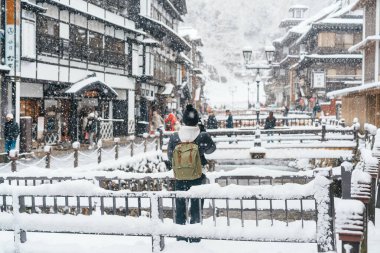 Yamagata 'da Ginzan Onsen' i ziyaret eden kadın turist, mutlu gezgin kış mevsiminde Snow ile Japon Onsen köyünü geziyor. Japonya 'da bir dönüm noktası ve popüler. Seyahat ve Tatil kavramı