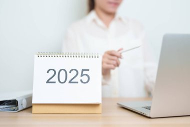 2025 Yıllık Takvim, iş kadınlarıyla masada dizüstü bilgisayar kullanarak, çalışarak ve yazarak. Geri sayım, Mutlu Yıllar, Çözünürlük, Yıl sonu ve Yeni Başlangıç ve Hedefler Planlama Eylemi