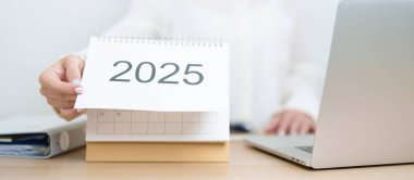 2025 Yıllık Takvim, iş kadınlarıyla masada dizüstü bilgisayar kullanarak, çalışarak ve yazarak. Geri sayım, Mutlu Yıllar, Çözünürlük, Yıl sonu ve Yeni Başlangıç ve Hedefler Planlama Eylemi