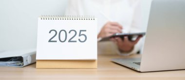 2025 Yıllık Takvim, iş kadınlarıyla masada dizüstü bilgisayar kullanarak, çalışarak ve yazarak. Geri sayım, Mutlu Yıllar, Çözünürlük, Yıl sonu ve Yeni Başlangıç ve Hedefler Planlama Eylemi