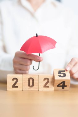 2024 yılı bitiminde kırmızı şemsiyeli mutlu yıllar 2025. Sigorta, koruma, güvenlik ve yeni yıl tatili kavramları