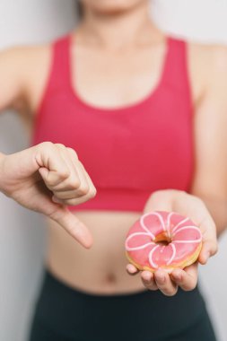 Kadın elinde mezurayla donut tutuyor, tatlı yemeyi bırakmayı seçiyor sağlıksız yiyecekler. Diyet kontrolü, kilo kaybı, obezite, yeme tarzı ve beslenme kavramları