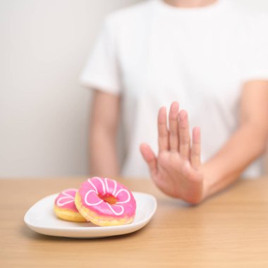 Kadın eli çöreği reddediyor, kadın sağlıksız abur cuburu reddediyor. Diyet kontrolü, kilo kaybı, obezite, yeme tarzı ve beslenme kavramları