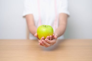 Yeşil Elma 'yı mezurayla tutan kadın, mutlu kadın meyvesini seçer sağlıklı yemektir. Diyet kontrolü, kilo kaybı, obezite, yeme tarzı ve beslenme kavramları