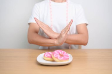 Kadın eli çöreği reddediyor, kadın sağlıksız abur cuburu reddediyor. Diyet kontrolü, kilo kaybı, obezite, yeme tarzı ve beslenme kavramları