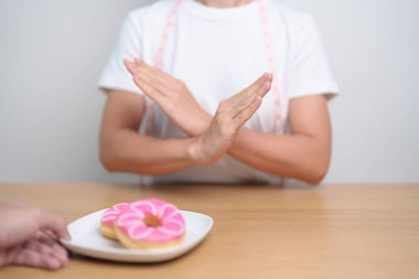 Kadın eli çöreği reddediyor, kadın sağlıksız abur cuburu reddediyor. Diyet kontrolü, kilo kaybı, obezite, yeme tarzı ve beslenme kavramları