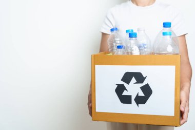 Gönüllü, plastik şişeyi evde ya da ofiste karton kutuya koyuyor. Geri Dönüşüm çöpünü elle ayırmak. Ekoloji, Çevre, Kirlilik, Geri dönüşüm, Atık Yönetimi ve Çöp Ayrıştırma Konsepti