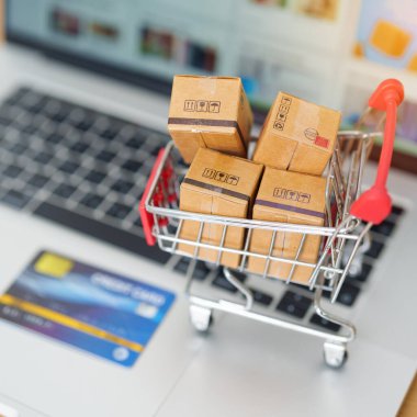 Dizüstü bilgisayarında kredi kartı olan kutular. Çevrimiçi alışveriş, Pazar yeri platformu web sitesi, teknoloji, ekommerce, nakliye teslimatı, lojistik ve çevrimiçi ödeme kavramları