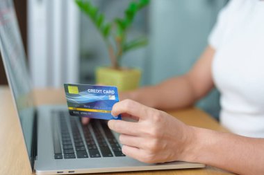 Kadın kredi kartını tutuyor ve evde sipariş verirken online alışveriş için dizüstü bilgisayar kullanıyor. Pazar yeri platformu web sitesi, teknoloji, ecommerce, dijital bankacılık ve çevrimiçi ödeme kavramı
