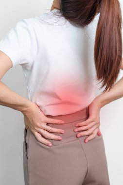 Gri arka planda kas ağrısı olan yetişkin bir kadın. Piriforis Sendromu, bel ağrısı ve omurga baskısı nedeniyle sırt ağrısı çeken yaşlı bir kadın. Ofis sendromu ve tıbbi konsept