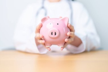 Doktor kumbarayı tutuyor ve para koyuyor. ve sağlık giderleri, para tasarrufu, sağlık sigortası, sağlık, bağış ve finansal kavramlar
