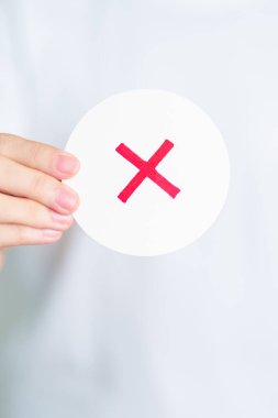 Kadın yanlış sembol kağıdı göstermiş. Doğru ve yanlış, kabul et ve reddet, değerlendirme, oy ver, oy ver, evet ya da hayır ve araştırma kavramları
