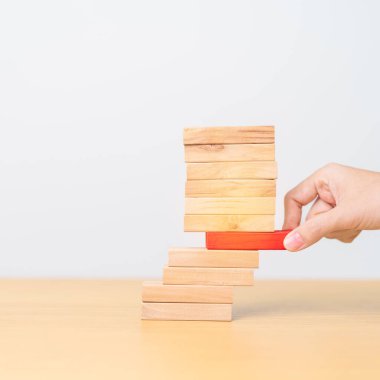 Kadın eli masadaki tahta domino taşlarını çekiyor. Kriz, Sonbahar İşletmeleri, Risk Yönetimi, Ekonomik durgunluk, Strateji ve Çözümler Konsepti