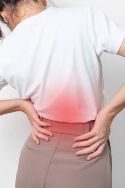 Gri arka planda kas ağrısı olan yetişkin bir kadın. Piriforis Sendromu, bel ağrısı ve omurga baskısı nedeniyle sırt ağrısı çeken yaşlı bir kadın. Ofis sendromu ve tıbbi konsept