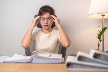 Kadın iş kadınının başı ağrıyor, migreni var, Asyalı kadının çalışırken yorgun ve stresli olması, gece yarısı evde evrak klasörleri olan bitkin bir kadın. Fazla çalışma ve fazla mesai