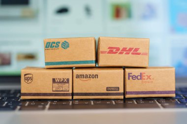 Nakliye kutuları dizüstü bilgisayarda. Dünya çapında popüler nakliye ve lojistik şirketi, Amazon, DHL, FedEx, UPS ve OCS ekspres çevrimiçi alışveriş. Bangkok, Tayland, 11 Haziran 2023