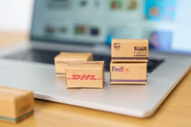 Shipping Boxes on laptop. Popular worldwide shipping and logistic company, Amazon, DHL, FedEx, UPS and OCS express delivery from online shopping. Bangkok, Thailand, 11 June 2023 clipart