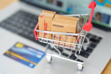 Bilgisayarında kredi kartı olan kargo kutuları. Dünya çapında popüler nakliye ve lojistik şirketi, Amazon, DHL, FedEx, UPS ve OCS ekspres çevrimiçi alışveriş. Bangkok, Tayland, 11 Haziran 2023