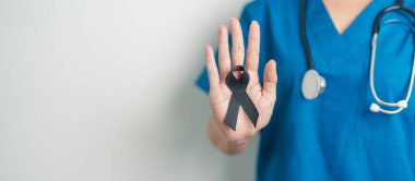 Melanoma ve cilt kanseri, aşı hasarı farkındalığı ayı ve huzur içinde yatma kavramları. Doktor elinde siyah kurdele tutuyor.