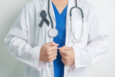 Melanoma ve cilt kanseri, aşı hasarı farkındalığı ayı ve huzur içinde yatma kavramları. Doktor elinde siyah kurdele tutuyor.