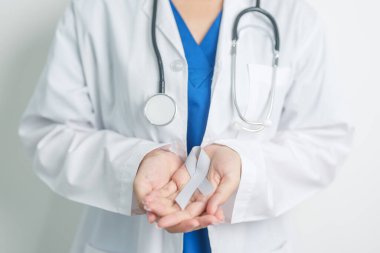 Beyin Kanseri Farkındalığı Mayıs ayında, gri renkli kurdeleli doktor, yaşam insanlarını desteklediği için. Sağlık ve Dünya Kanser Günü konsepti