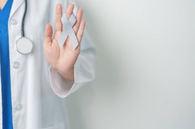 Beyin Kanseri Farkındalığı Mayıs ayında, gri renkli kurdeleli doktor, yaşam insanlarını desteklediği için. Sağlık ve Dünya Kanser Günü konsepti