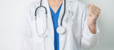 Beyin Kanseri Farkındalığı Mayıs ayında, gri renkli kurdeleli doktor, yaşam insanlarını desteklediği için. Sağlık ve Dünya Kanser Günü konsepti