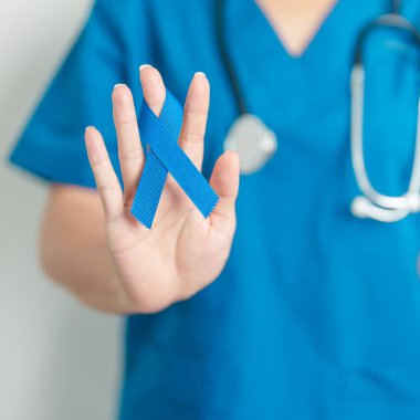 March Colectal Kanser Farkındalığı Ayı. Koyu mavi kurdeleli bir doktor. Yaşayan ve hastalıklı insanları destekliyor. Sağlık, umut ve Dünya Kanser Günü konsepti