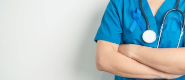 March Colectal Kanser Farkındalığı Ayı. Koyu mavi kurdeleli bir doktor. Yaşayan ve hastalıklı insanları destekliyor. Sağlık, umut ve Dünya Kanser Günü konsepti