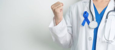 March Colectal Kanser Farkındalığı Ayı. Koyu mavi kurdeleli bir doktor. Yaşayan ve hastalıklı insanları destekliyor. Sağlık, umut ve Dünya Kanser Günü konsepti