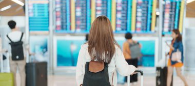 Havaalanı, ulaşım, sigorta, seyahat ve tatil konseptlerinde uçuş süresini kontrol etmeden önce el ele tutuşan genç kadın.