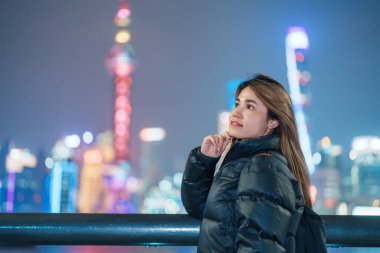 woman traveler visiting in Shanghai, China. Happy Female Tourist sightseeing Shanghai view of Lujiazui in The Bund of Shanghai at night. landmark and popular for tourism attractions. Vacation concept clipart