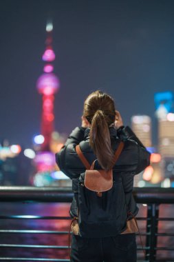 Çin, Şangay 'ı ziyaret eden bir kadın gezgin. Sırt çantalı bir bayan turist Şangay 'da Lujiazui' nin Şangay 'daki Bund of Shanghai manzarasını seyrediyor. tarihi eser ve turizm turizmi için popüler.