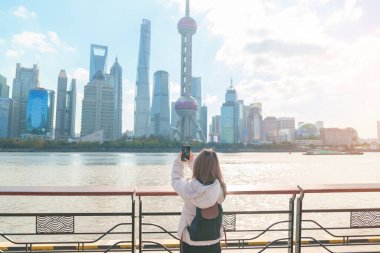Çin, Şangay 'ı ziyaret eden bir kadın gezgin. Sırt çantalı bayan turist Şangay 'ın kuzeyindeki Lujiazui' nin Şangay manzarasına bakıyor. tarihi eser ve turizm turizmi için popüler.